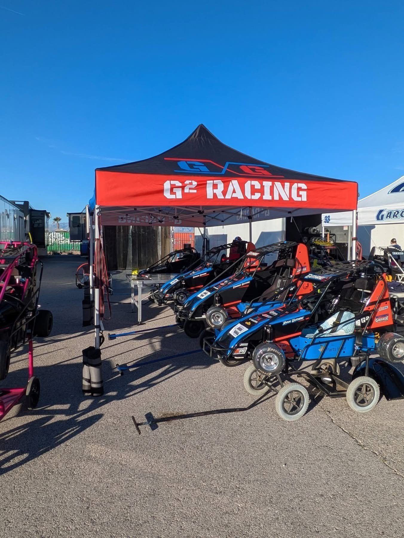 The G² Racing canopy in the paddock with cars lined up beneath it